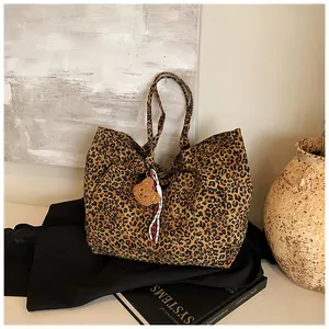 Detailansicht der Leopard-Print-Einkaufstasche mit Bärenanhänger vor stylischem Dekor