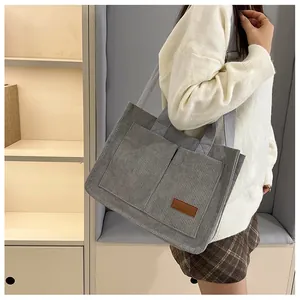 Detail of grey corduroy tote bag with dual front pockets and woven shoulder strap