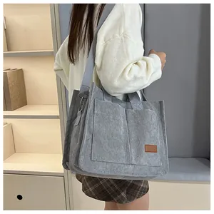 Side view of a large grey corduroy tote bag with adjustable straps and front pockets