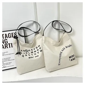 Dettaglio della borsa tote in tela con scritte minimaliste e tracolle resistenti