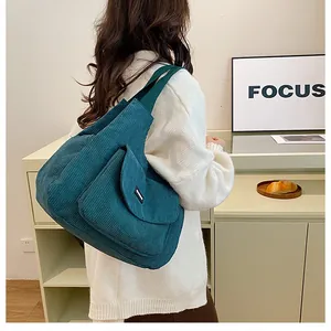 Detail of dark green corduroy tote bag with front pocket and soft texture on shoulder
