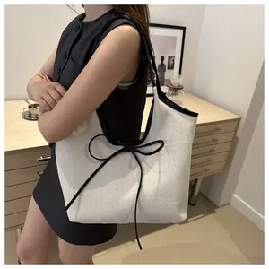 Close-up of the large black leather bow detail and herringbone fabric texture on the tote bag