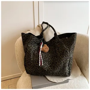 Detail einer Leopard-Tote-Bag mit braunem Bärenanhänger und geflochtener Kordelverzierung