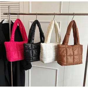 Dettaglio di borse tote trapuntate nei colori magenta, nero, bianco e marrone su grucce