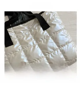 Détail d'un sac cabas en nylon blanc matelassé avec finition brillante et anses noires