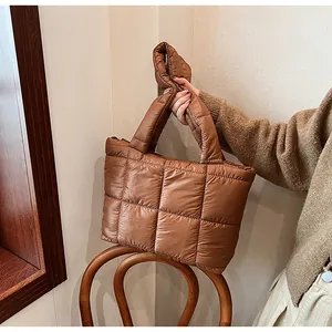 Dettaglio di una borsa tote marrone trapuntata con imbottitura in nylon su legno