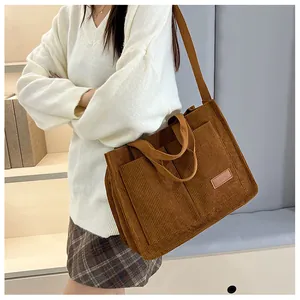 Detail of dark brown corduroy tote bag with dual straps and leather fashion label