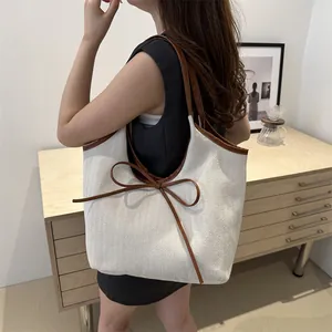 Large beige canvas tote bag with brown leather handles in a cozy home interior setting