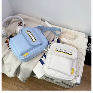 Detail view of light blue and white canvas crossbody phone bags on a white suitcase