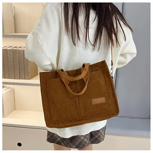 Close-up of caramel corduroy tote bag featuring front pockets and a leather fashion tag