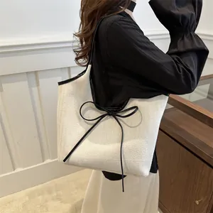 French style herringbone tote bag with black bow and leather strap worn by a model