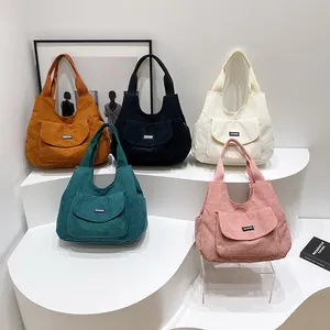 Five colors of corduroy tote bags with front pockets displayed in a minimalist studio set