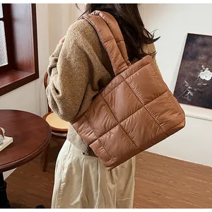 Vista dettagliata della borsa tote imbottita marrone indossata da una modella in interno