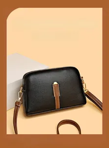 Detailed view of black litchi pattern leather shell bag with gold zippers and brown straps