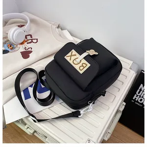 Detail of black canvas messenger bag with BOX label and cute white bear keychain accessory