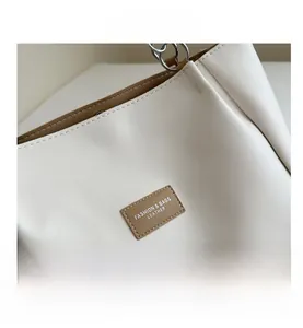Close-up of cream PU leather tote bag with brown trim and silver chain shoulder strap
