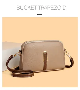 Detail view of khaki trapezoid crossbody bag with litchi texture and gold hardware
