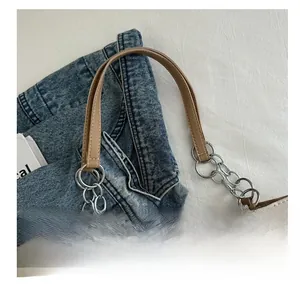 Detail of cream and brown tote bag with silver chain links and leather handles
