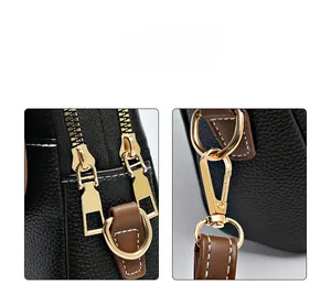 Detail of black pebbled leather texture with dual gold zippers and metallic D-ring hook