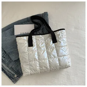 Détail d'un sac cabas matelassé blanc brillant avec des anses en sangle noire