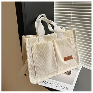 Detail of cream corduroy tote bag featuring dual front pockets and soft ribbed texture
