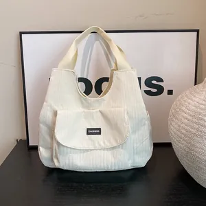Off-white corduroy tote bag with front pocket and logo label for casual daily use