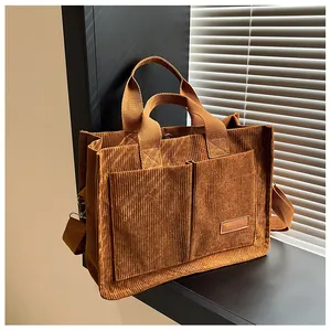 Detailed view of caramel corduroy tote bag showing front pockets and leather fashion label