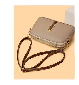 Detail of lychee pattern leather on beige crossbody bag with gold double zippers