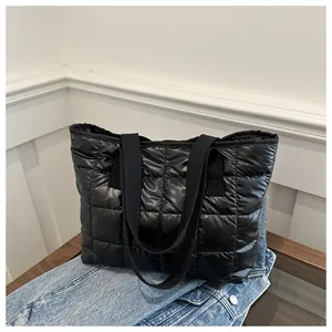 Détail macro du sac cabas matelassé noir montrant le motif de losanges et sa capacité