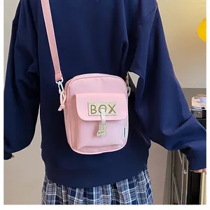 Pink canvas mini crossbody bag with cute bear pendant shown on model back