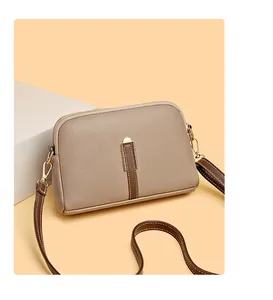 Detail view of khaki pebbled leather crossbody bag with brown straps and gold hardware