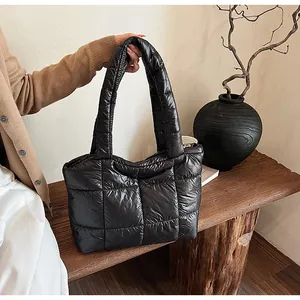 Dettaglio della borsa shopper nera trapuntata in nylon lucido su panca di legno