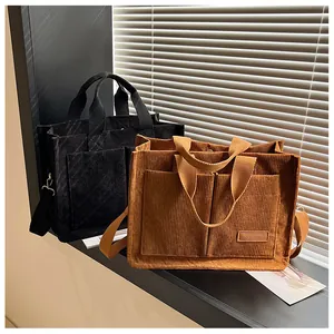 Detail view of corduroy tote bag showing front pockets and adjustable shoulder strap