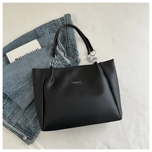 Detail of black leather tote bag with silver chain handles and fashion logo patch