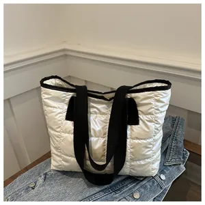 Détail du sac fourre-tout matelassé blanc perle avec anses en toile noire sur denim