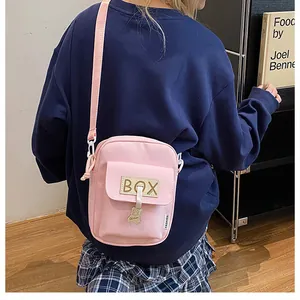 Detail of pink canvas crossbody phone bag featuring a cute bear pendant and adjustable strap