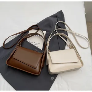 Bruine en beige leren crossbodytassen op een grijze blazer voor dagelijks woon-werk