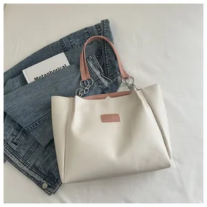 Detail of cream tote bag with pink inner lining, metal chains and leather tag