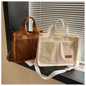 Detail of corduroy tote bags with dual front pockets and brown leather fashion label