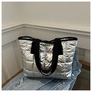 Gros plan d'un sac cabas argenté matelassé avec des anses noires sur un fond denim