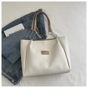 Close-up of beige tote bag with chain strap, PU leather texture, and aesthetic props