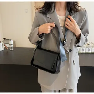 Detail van zwarte kunstlederen crossbodytas met verstelbare riem en klepsluiting