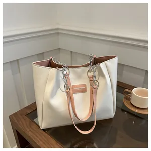 Detail of minimalist cream tote bag with pink leather trim and embossed brand label
