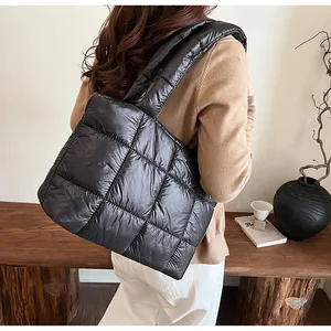 Vista laterale della borsa tote trapuntata nera con spalline larghe in un ambiente minimalista