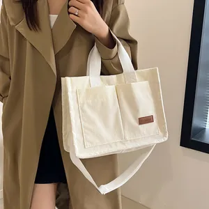 Off-white corduroy tote bag with large front pockets and adjustable strap for women