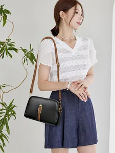 Chic black textured shell bag with brown adjustable leather strap on a female model