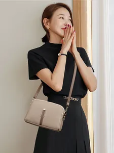 Chic taupe crossbody bag in pebble leather worn with a stylish black outfit