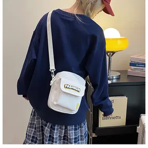 Detail of white canvas crossbody bag featuring Fashion embroidery and flap pocket