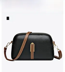 Detail of black lychee grain leather crossbody bag with brown strap and gold-tone hardware