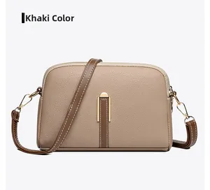 Detail view of khaki crossbody bag showing litchi grain texture and gold hardware hooks